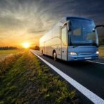 Bus driving on a road at sunset