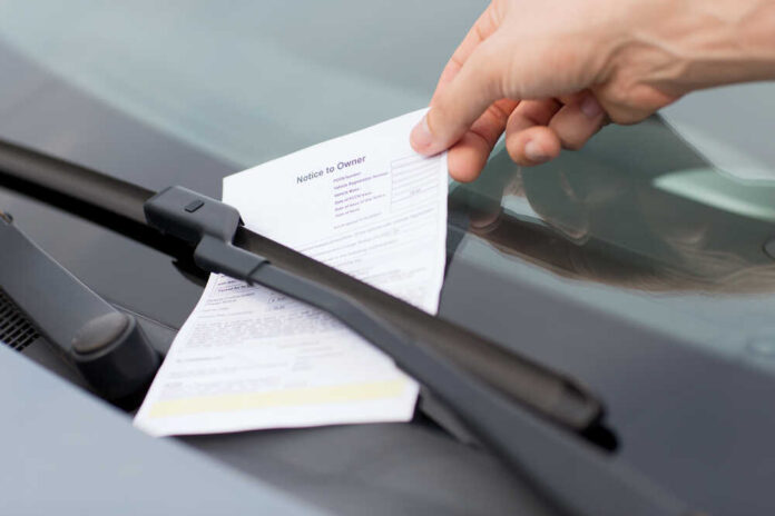 152527700 featured image Hand retrieving parking ticket from car windshield