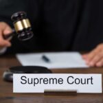 Judge with gavel and Supreme Court nameplate