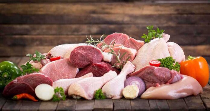 Assorted raw meat with vegetables on wooden table