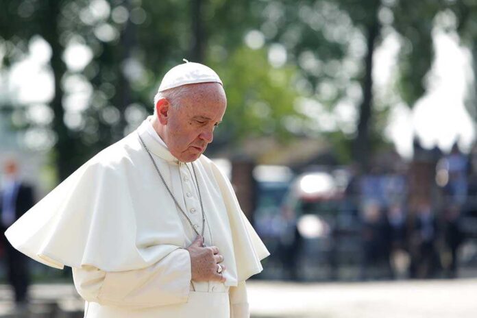 Man in white religious attire looking down thoughtfully