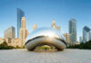 Cloud Gate sculpture with skyline of skyscrapers behind it