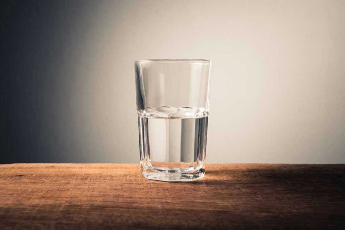 Glass of water half full on table