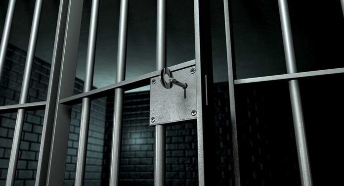shutterstock_108487772.jpg Close up of a locked prison gate with metal bars