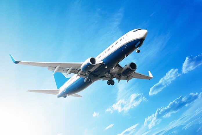 shutterstock_111203738.jpg An airplane flying against a clear blue sky with clouds
