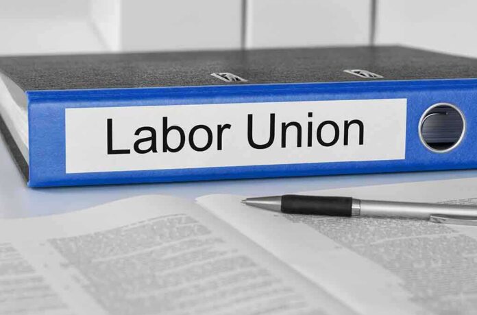 A black binder labeled Labor Union placed on a desk with papers and a pen