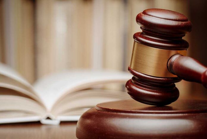 A wooden gavel resting on a sound block with law books in the background