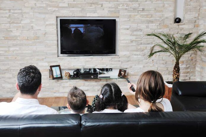 A family of four watching television together in a cozy living room