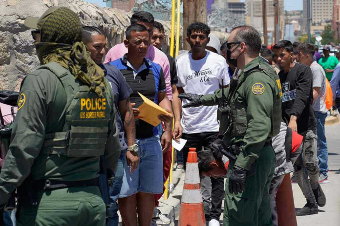 Border patrol agents inspecting group of individuals in line