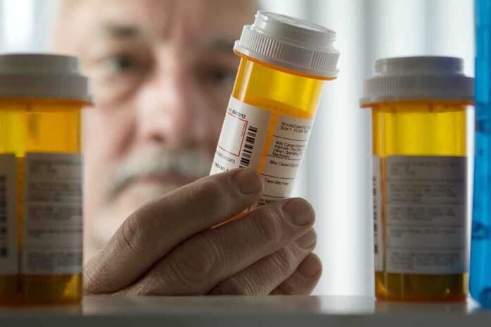 An elderly man holding a prescription bottle while examining it closely