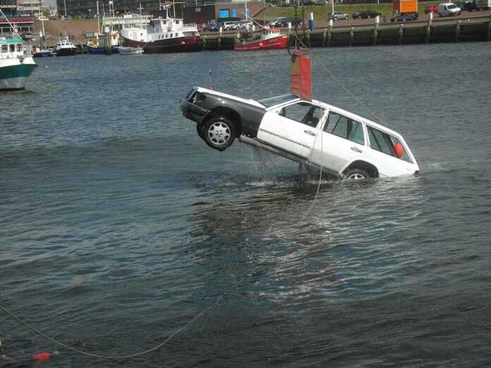 shutterstock_4202062.jpg A white car being lifted out of the water by a crane at a port