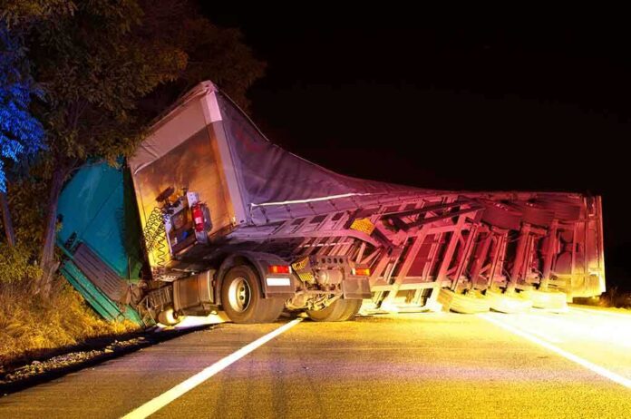 An overturned truck on the side of the road at night with emergency lights