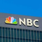 NBC logo displayed on a building against a clear blue sky
