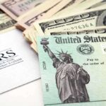 A tax refund check from the IRS alongside various denominations of cash