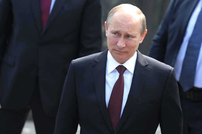 A serious-looking man in a suit walking outdoors with security personnel in the background