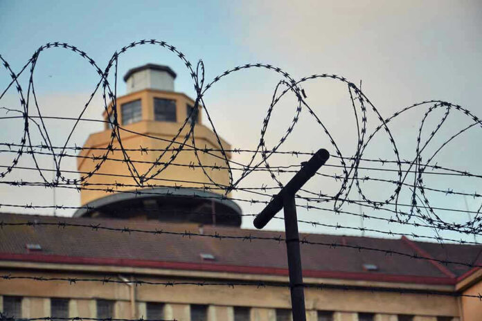 Barbed wire in front of a prison tower.