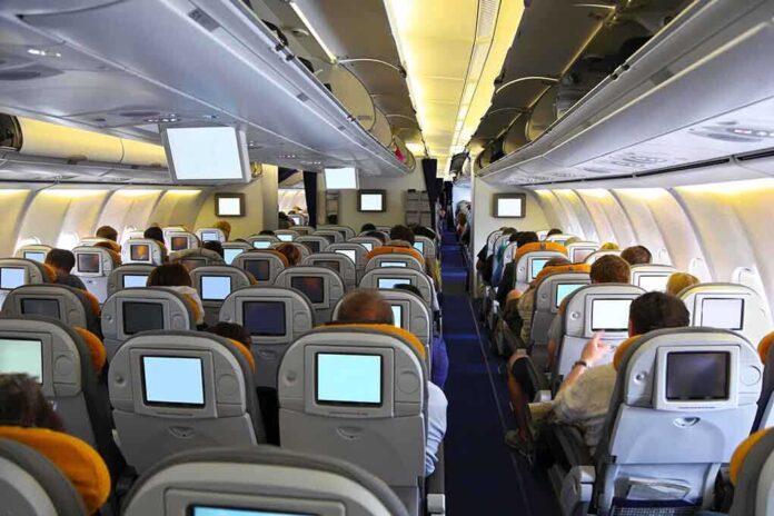 Interior view of an airplane with passengers seated and using in-flight entertainment screens