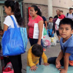 American Child DEPORTED — Constitutional Crisis Unfolds People waiting outside carrying bags, boys sitting and playing.