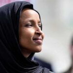 Ilhan Omar SQUIRTED With Unknown Liquid During Protest! A woman wearing a black hijab looking thoughtfully during an outdoor event