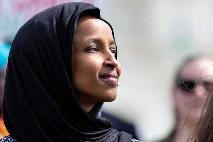 A woman wearing a black hijab looking thoughtfully during an outdoor event