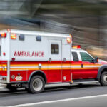 Red and white ambulance driving on street.