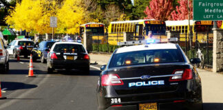 Police cars and school buses on a road.