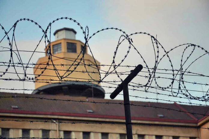 Barbed wire in front of a prison tower.