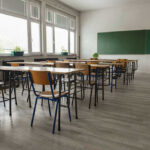 Scandal Exposed: Kindergarten Teacher’s Shocking Confession Empty classroom with desks, chairs, windows, and chalkboard.