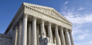 Exterior view of the Supreme Court building with columns and a statue of justice