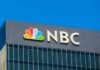 NBC logo displayed on a building against a clear blue sky