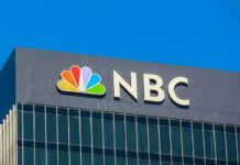 NBC logo displayed on a building against a clear blue sky