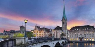 Scenic view of Zurich with a bridge, historic buildings, and a sunset sky