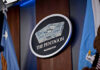 Pentagon Hires Convicted Jan. 6 Rioter For TOP Position The Pentagon emblem between two flags.