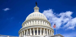 The U.S. Capitol building with a dome and American flag against a blue sky