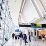 Interior of an airport terminal with travelers and signage