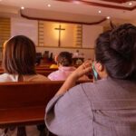Knifeman STABS Woman Praying During Mass people seated in church pews facing a cross