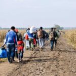 Group of people walking along a muddy rural path between fields