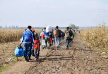 Group of people walking along a muddy rural path between fields