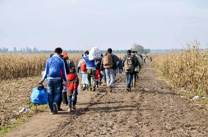 shutterstock_1820261090 Group of people walking along a muddy rural path between fields