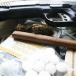 Handgun with cash, pills, and marijuana on a table