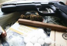 Handgun with cash, pills, and marijuana on a table