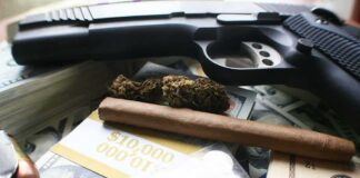 Handgun with cash, pills, and marijuana on a table