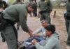 ICE Agents Tease Starving Kids Inside Facility law enforcement officer handcuffing two seated men outdoors