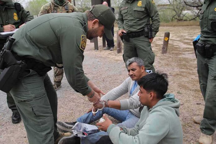 shutterstock_2270044315 law enforcement officer handcuffing two seated men outdoors