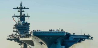 Aircraft carrier guided by tugboats in a harbor