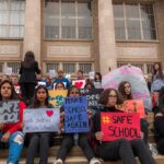 Students holding protest signs on school steps