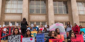 Students holding protest signs on school steps
