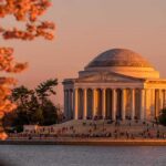 Jefferson Memorial at sunset with cherry blossoms and visitors by the water