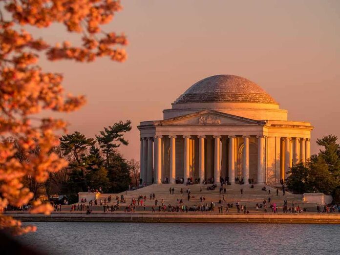 Jefferson Memorial at sunset with cherry blossoms and visitors by the water