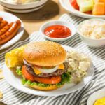 Cheeseburger on a plate with potato salad and corn on the cob
